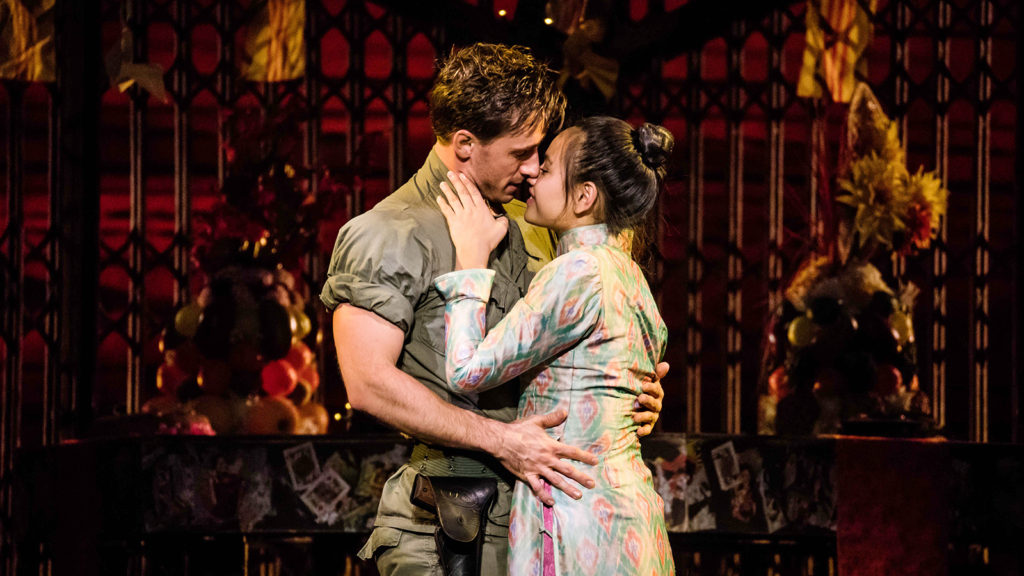 Photograph of miss saigon musical with Vietnamese women and a white american imperialist soldier embracing