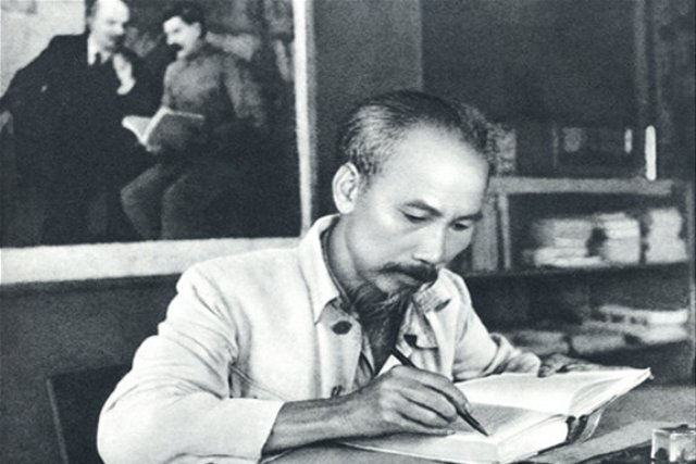 black and white photograph of Ho Chi Minh writing in a notebook