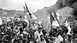Black and white photograph of a crowd of Algerian people proudly holding up the Algerian flag to celebrate Algerian Independence Day