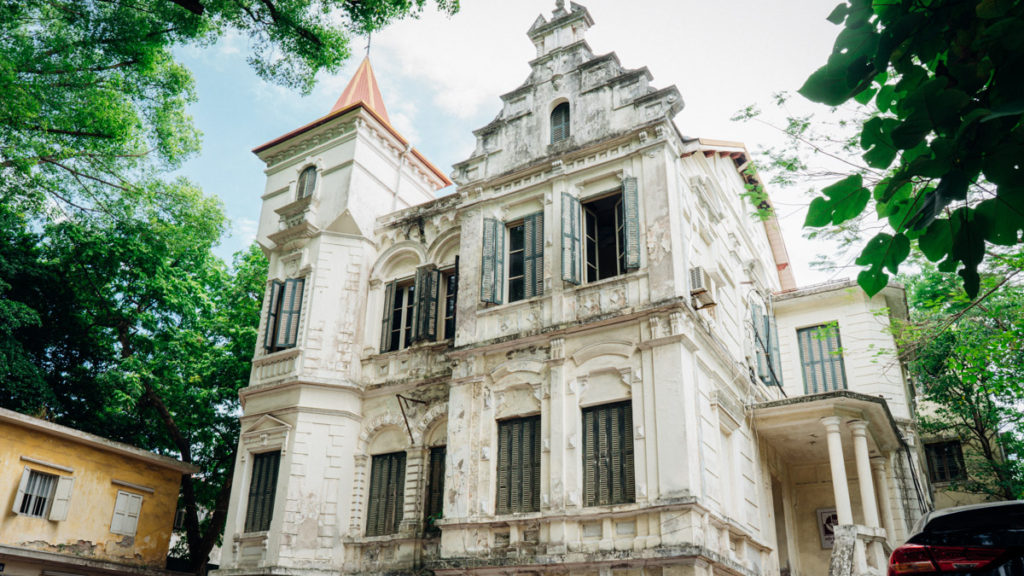 An antique building in Hanoi, Viet Nam built by French colonizers. The building is white and appears to have not been repainted on the exterior